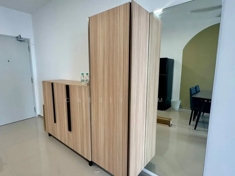 Room features: wooden cabinetry with vertical handles, light wood finish, floor-to-ceiling storage unit, glossy tile flooring, neutral wall color, visible dining area in background, two water bottles on top of cabinetry; style: modern.