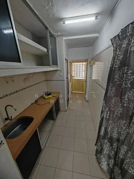 Room features: single-bowl stainless-steel sink, wood countertop, white tiled walls, cream tiled flooring, built-in cabinets with glass doors, curtain with floral pattern, light fixture on ceiling, open space leading to another room.
