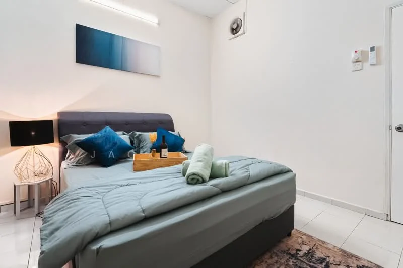 Bedroom features: queen-size bed with grey bedding, upholstered headboard, decorative pillows in blue, bedside table with geometric lamp, wooden serving tray on bed, rolled towels, wall-mounted air conditioning unit, white painted walls, tile flooring, area rug with geometric pattern, framed artwork above bed, recessed lighting; style: modern.