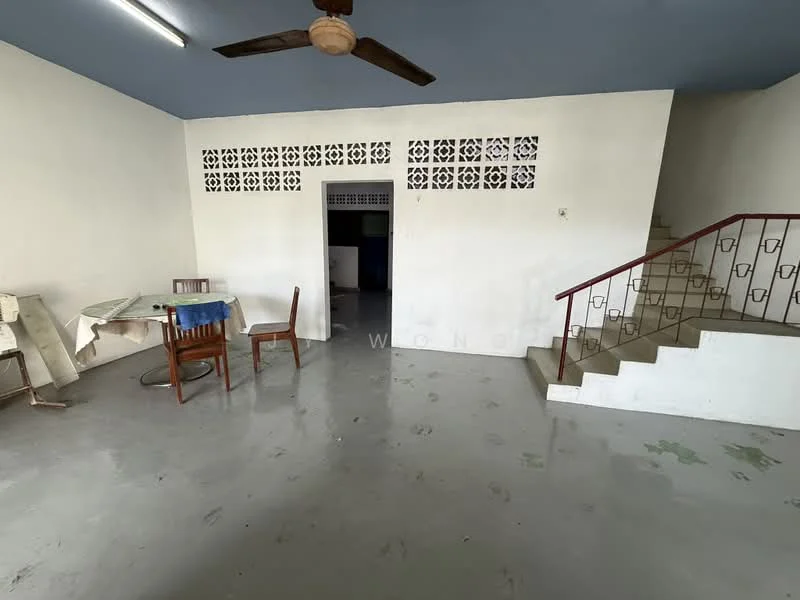 Room features: grey polished concrete flooring, white painted walls, ceiling fan, wooden dining table with blue tablecloth, wooden chair, staircase with metal railing, decorative ventilation blocks, open layout; style: minimalist.