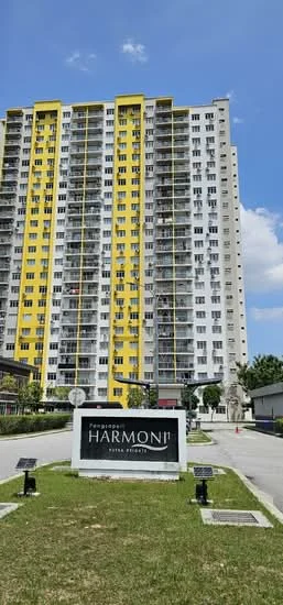 Exterior type: high-rise condominium; features: yellow and white painted facade, glass balcony railings, approximately 15-storey high-rise, landscaped garden area, signage at entrance, manicured lawn, parking area, surrounded by greenery; style: modern.