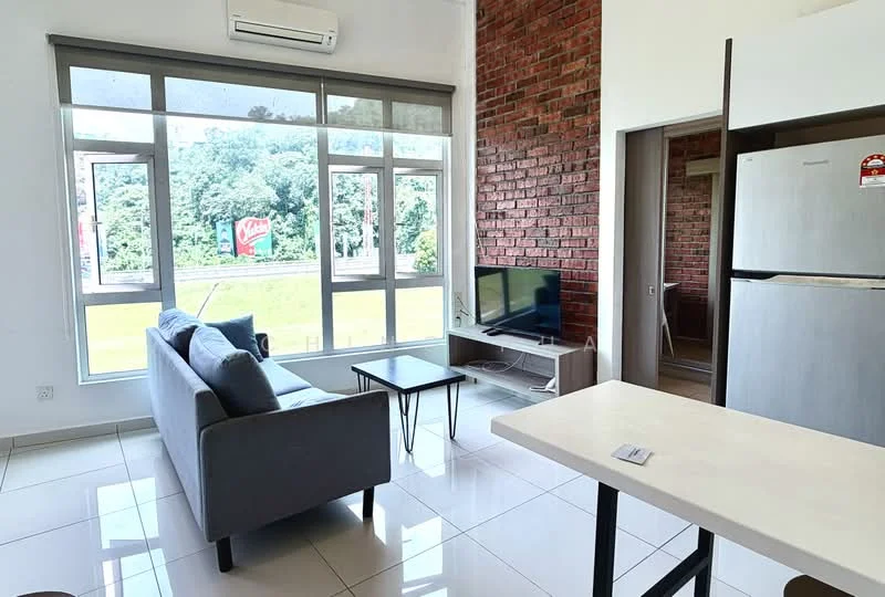Living features: grey fabric sofa, coffee table, wall-mounted TV, exposed brick accent wall, white painted walls, large windows with city view, air conditioning unit, ceramic tile flooring; style: modern; view: city. Kitchen features: stainless-steel fridge, kitchen island with countertop, open layout; style: modern.