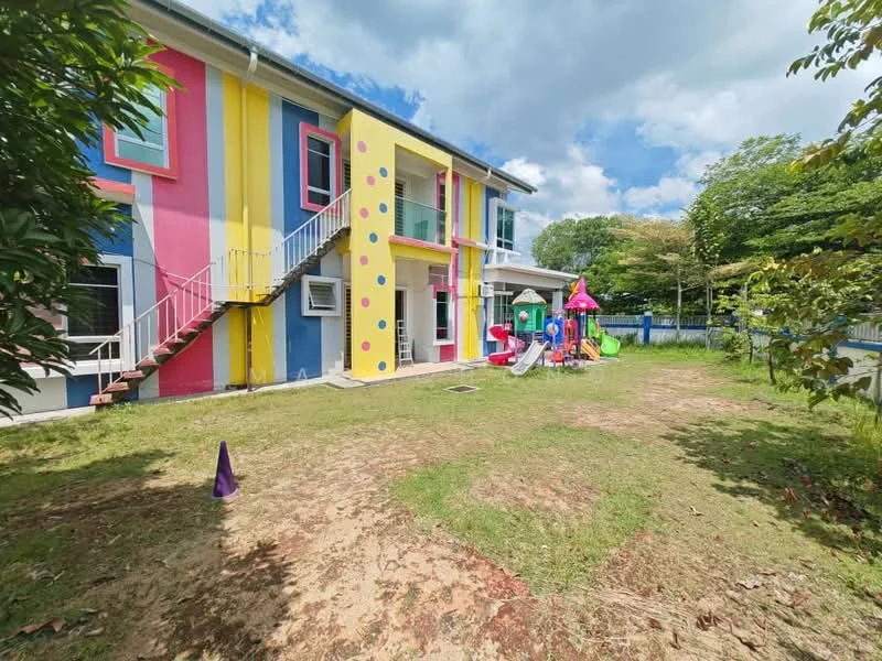 Exterior type: low-rise apartment block; features: colorful facade with yellow and pink walls, staircase leading to upper floor, playground equipment including slides and climbing structures, manicured lawn, surrounding greenery, outdoor space for recreation; style: modern.
