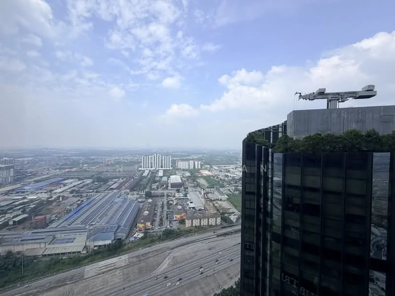 Exterior type: high-rise condominium; features: glass curtain wall, greenery on rooftop, surrounded by urban landscape, view of city skyline, highway visible in foreground, industrial buildings in distance; style: modern.