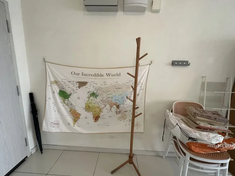 Room features: white painted walls, tile flooring, map wall hanging, wooden coat rack, stacked chairs, air conditioning unit, light switch, shelves; style: modern.