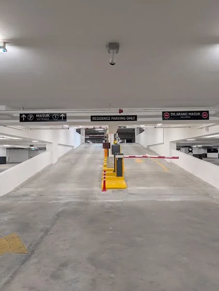 Exterior type: parking deck; features: multi-storey car park, concrete flooring, yellow painted ramp, signage for residence parking, barrier gate, white painted walls, LED lighting, open-air design; style: modern.
