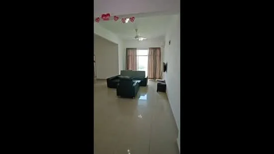 Living features: cream painted walls, glossy tile flooring, 5-blade ceiling fan with light, sofa in dark grey, coffee table, TV console, wall-mounted TV, floor-to-ceiling windows with sheer curtains, curtains in beige, decorative wall clock; style: modern; view: city.