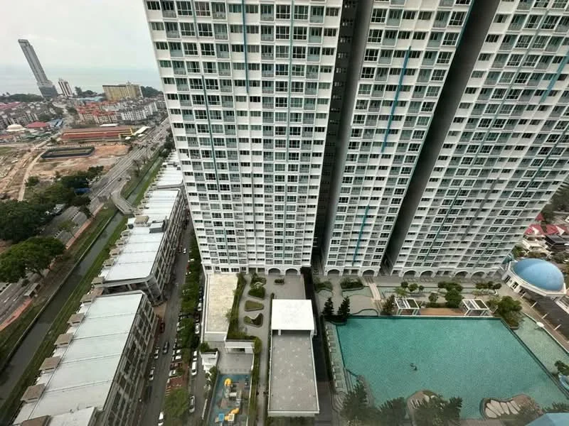 Exterior type: high-rise condominium; features: glass curtain wall, approximately 20-storey high-rise, infinity pool, pool deck with loungers, landscaped garden area, surrounded by mature greenery, adjacent to highway, city skyline view in background; style: modern.