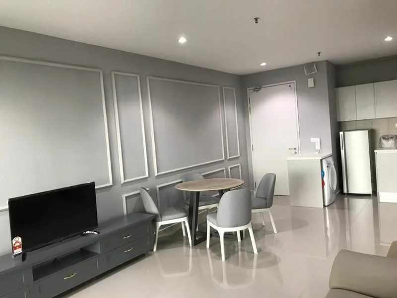 Living features: grey painted walls, glossy tile flooring, recessed downlights, wall-mounted TV, TV console, round dining table, 4 upholstered dining chairs, white cabinetry, refrigerator, door to hallway; style: modern.