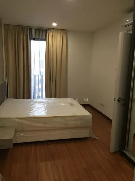Bedroom features: queen-size bed with mattress covered in plastic, wooden flooring, floor-to-ceiling window, sheer curtains, recessed downlights, built-in wardrobe, neutral wall colour, minimalist decor; style: modern; view: city.