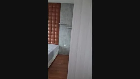 Bedroom features: wooden flooring, grey accent wall, upholstered headboard, shelving unit, queen-size bed, decorative wall paneling, neutral wall color, natural light from window; style: modern.