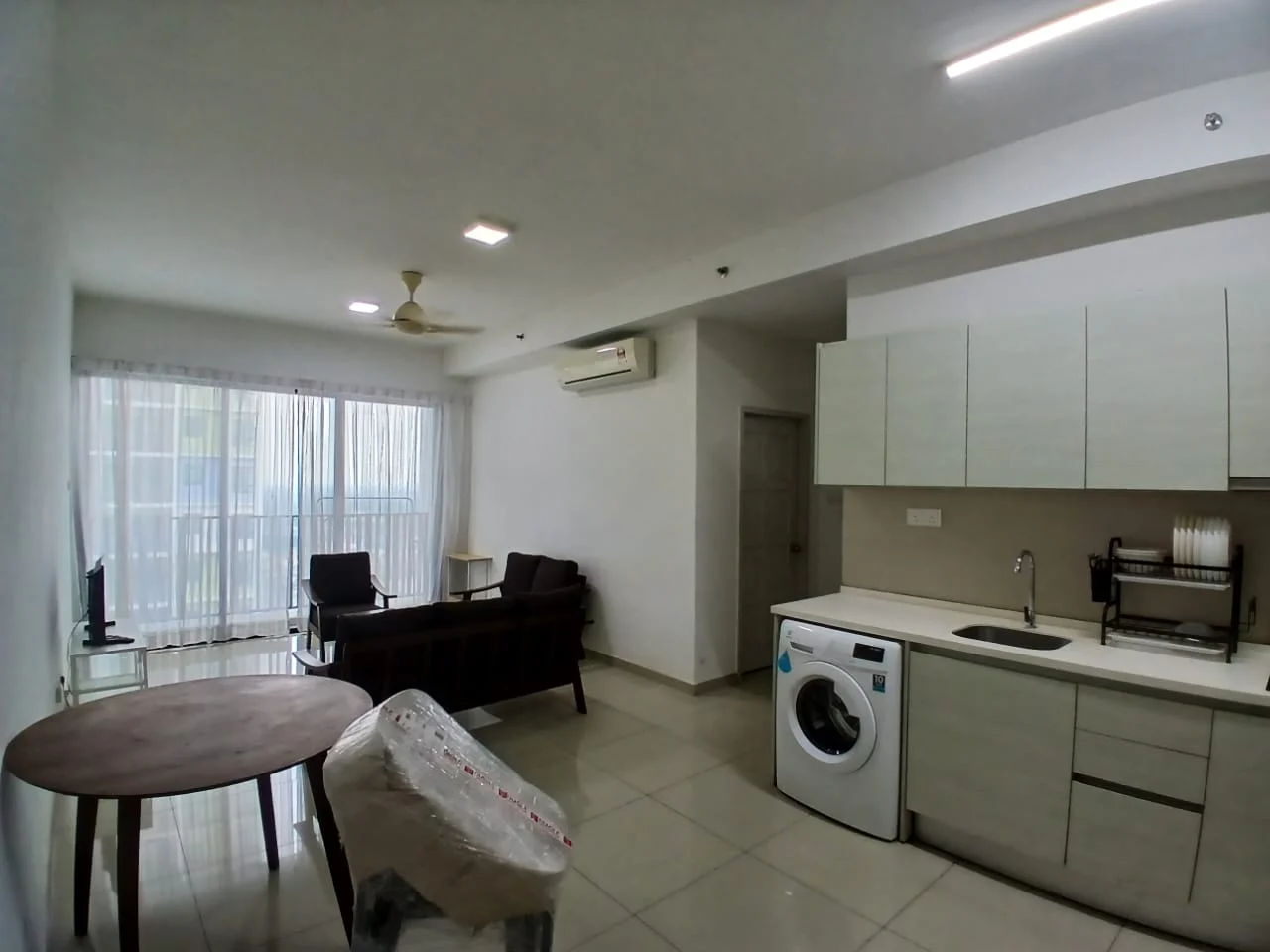 Living features: white painted walls, tile flooring, 5-blade ceiling fan with light, recessed LED downlights, floor-to-ceiling windows, sheer curtains, 2-seater fabric sofa in dark brown, wooden coffee table, TV console, wall-mounted TV, built-in cabinetry, washing machine, kitchen countertop with cabinets; style: modern.