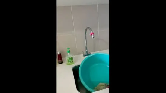 Kitchen features: single-bowl stainless-steel sink, chrome pull-down faucet, white countertop, light grey tiled backsplash, green plastic basin, dish soap, salt and pepper shakers.