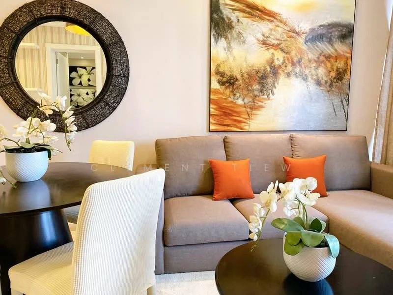 Living features: 3-seater fabric sofa in brown, orange accent cushions, round dining table, upholstered dining chairs in white, decorative wall art with abstract design, large round mirror, potted orchids on table, carpeted flooring, neutral wall color, curtains with light filtering; style: contemporary.