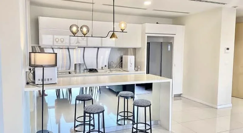 Kitchen features: white cabinetry, marble countertop, stainless-steel fridge, built-in oven, 4-burner gas hob, stainless-steel range hood, pendant lighting, bar stools, sink, backlit backsplash, tile flooring, open layout; style: modern.