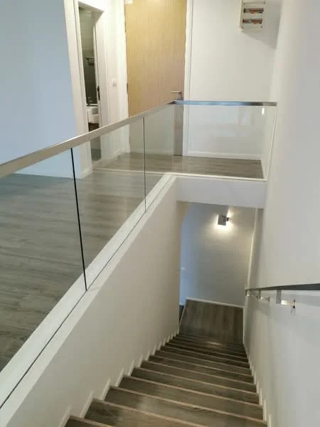 Room features: staircase with wooden steps, glass railing, white painted walls, recessed lighting, laminate flooring, doorway leading to another room, light fixture on wall; style: modern.