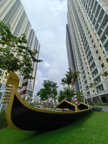 Exterior type: high-rise condominium; features: two high-rise buildings, landscaped green area, decorative gondola, palm trees, striped poles, modern architectural design, glass balconies, manicured lawn; style: modern.