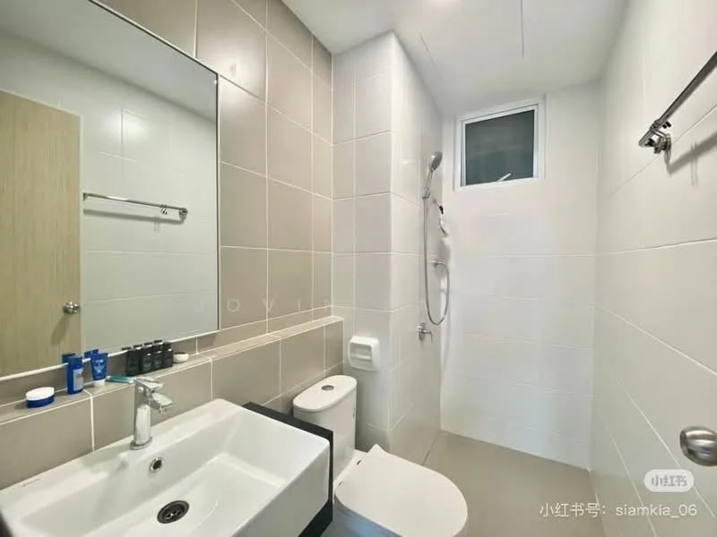 Bathroom features: white ceramic toilet, single-sink vanity with white cabinet, chrome basin mixer faucet, framed mirror, walk-in shower with glass enclosure, handheld shower, tile cladding on walls, grey tile flooring, window for natural light, wall-mounted towel bar, toiletries on vanity; style: modern.
