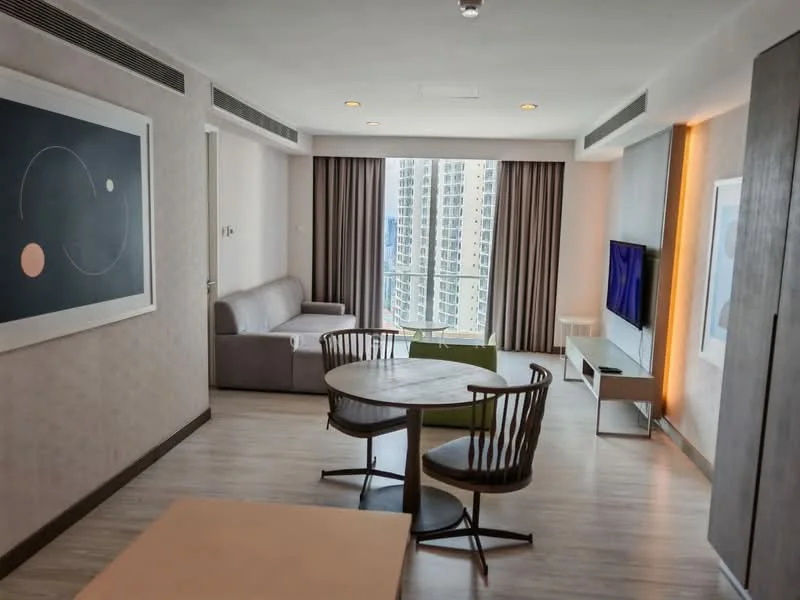 Living features: grey fabric sofa, round dining table, wooden dining chairs, wall-mounted TV, light wood flooring, floor-to-ceiling windows, sheer curtains, decorative wall art, recessed lighting, accent lighting, neutral wall colour, open layout; style: modern; view: city.
