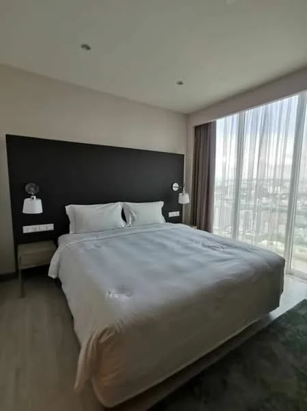 Bedroom features: king-size bed, upholstered headboard, two bedside lamps, nightstand, floor-to-ceiling windows, sheer curtains, wooden flooring, city view, recessed downlights, decorative wall with dark accent; style: modern; view: city.