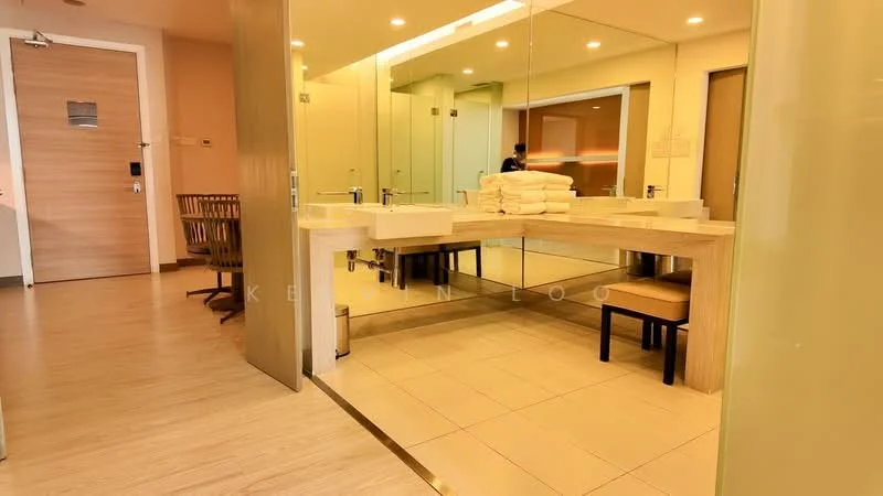 Bathroom features: double-sink vanity with wood cabinet, large mirror, lighted mirror, white ceramic sink, chrome basin mixer faucets, neutral tile flooring, wooden accents, towels stacked on vanity, seating area with chair, glass partition, recessed lighting; style: modern.