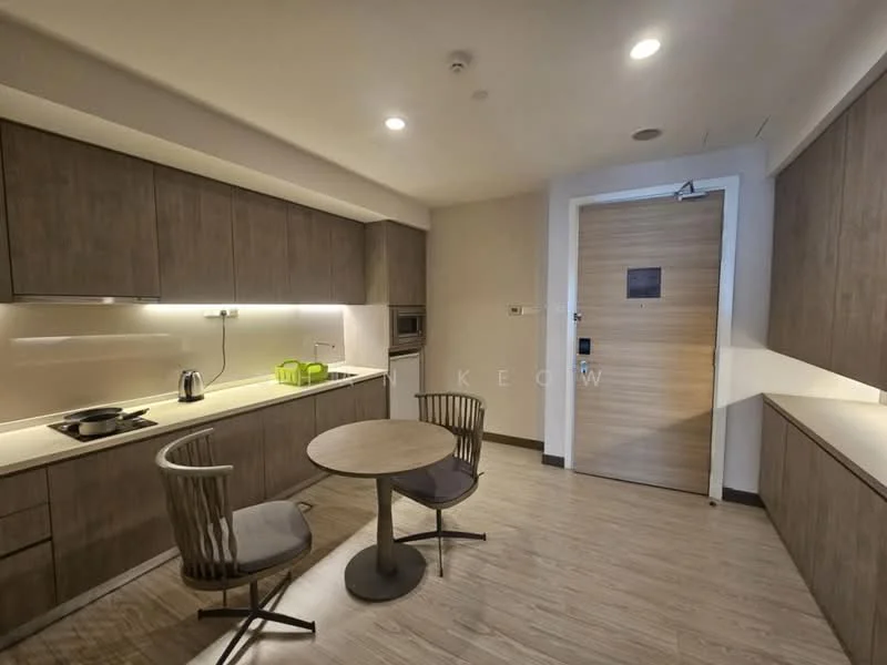 Kitchen features: brown wooden cabinetry, white countertop, built-in microwave, stainless-steel kettle, green glass canisters, 2-seater round dining table, 2 dining chairs with wooden legs, recessed LED downlights, laminate flooring, door leading to hallway; style: modern.