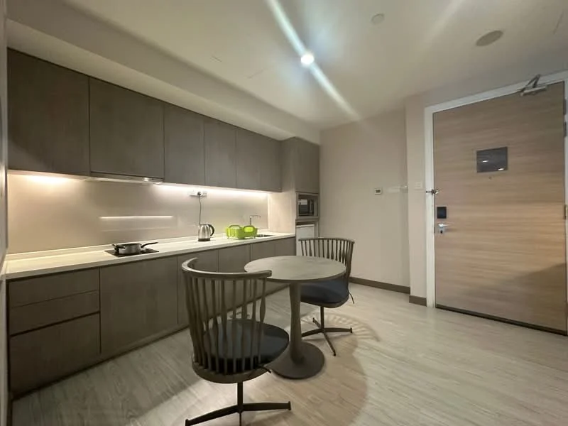 Kitchen features: grey cabinetry, white countertop, built-in microwave, stainless-steel sink, chrome faucet, kettle, 4-seater round dining table, 2 dining chairs, recessed downlights, wooden flooring, wall-mounted cabinet, open shelving; style: modern.
