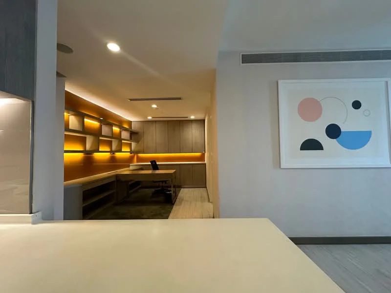Study features: built-in wooden desk, wall-mounted shelves, ambient lighting, neutral wall colour, wooden flooring, modern artwork on wall, office chair, recessed ceiling lights; style: modern.