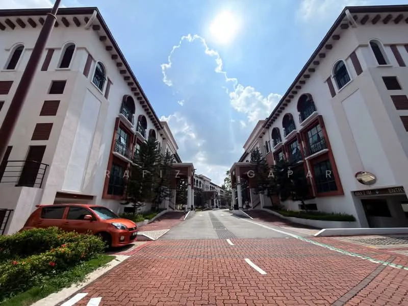 Exterior type: linked terrace house; features: red brick paved road, white painted facade, brown timber accents, two-storey buildings, manicured landscaping, mature trees, outdoor parking area, clear blue sky, clouds in the background; style: colonial.