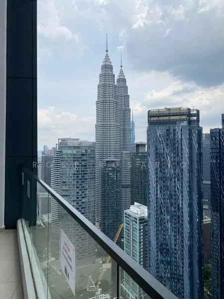 Exterior type: high-rise condominium; features: glass balcony railing, city skyline view, surrounded by modern skyscrapers, Petronas Twin Towers visible, urban landscape, cloudy sky; style: modern.