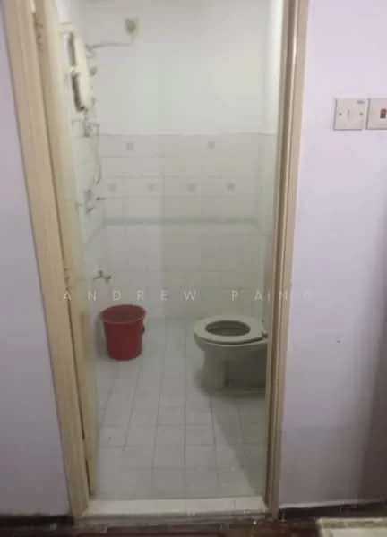 Bathroom features: white tiled walls, white tiled flooring, toilet, shower area, sink, plumbing fixtures, light fixture, red bucket.