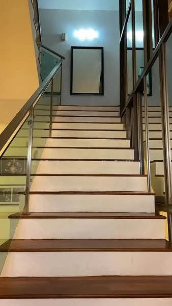 Room features: wooden staircase with white risers, glass railing, recessed ceiling lights, framed mirror on wall, neutral wall color, decorative wall art, open space at the top of the stairs; style: modern.