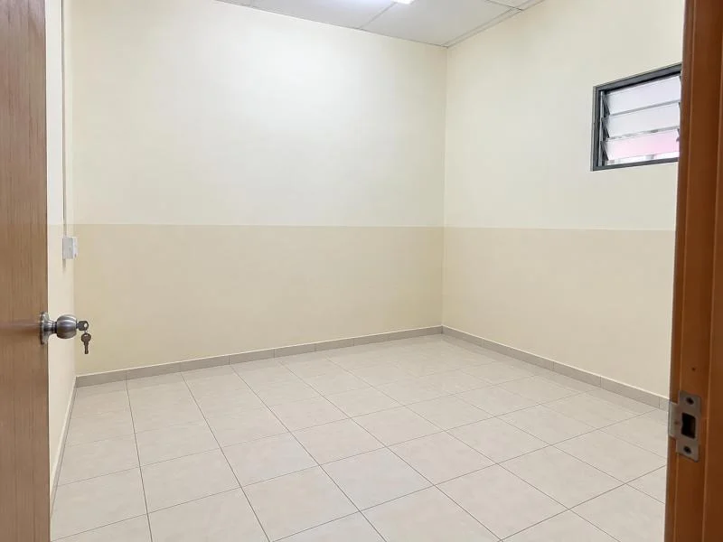 Room features: white painted walls, cream painted lower wall section, ceramic tile flooring, plain white ceiling, fluorescent ceiling light, small louvered window with metal frame, wooden door, metal door handle with key inserted, baseboard skirting; style: minimalist.