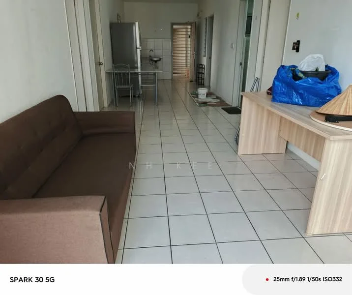 Living features: brown fabric sofa, tile flooring, white painted walls, refrigerator, metal shelving unit, wooden desk, blue plastic bag, doorway leading to hallway.