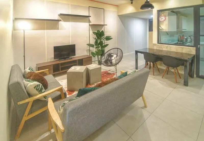 Living features: grey fabric 3-seater sofa, wooden armchair with black cushion, coffee table with concrete blocks, area rug with geometric pattern, TV console with TV, indoor plant, wall-mounted shelves, pendant light, large window with view to adjacent room, dining table with 4 black chairs, tile flooring, neutral wall color; style: modern.