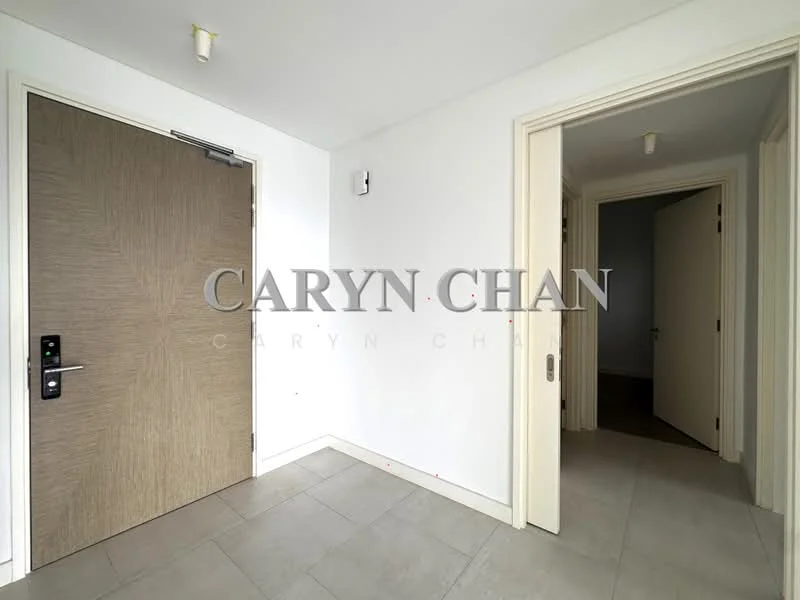 Room features: white painted walls, grey tiled flooring, wooden door with handle, light fixtures on ceiling, door frame, corner wall, empty space, no visible furniture; style: modern.