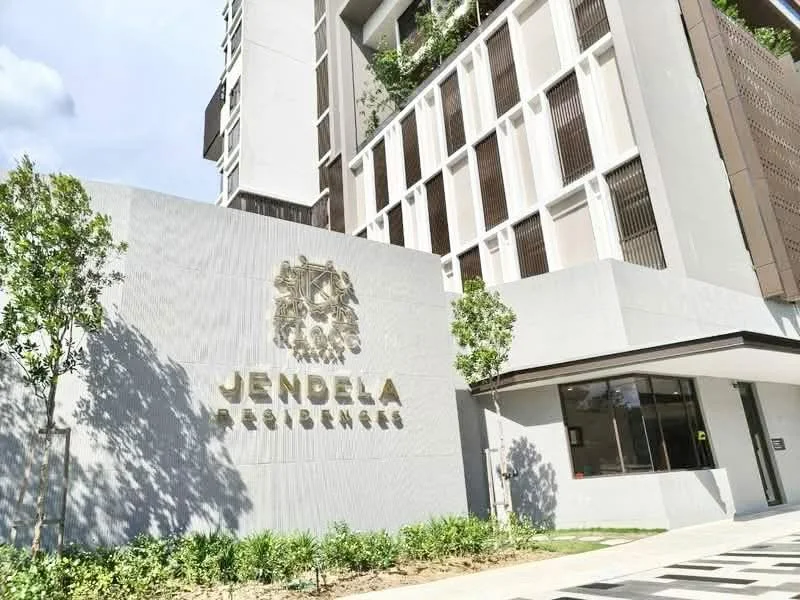 Exterior type: high-rise condominium; features: white painted facade, glass curtain wall, landscaped entrance with greenery, feature signage, covered entrance, modern architectural design; style: modern.