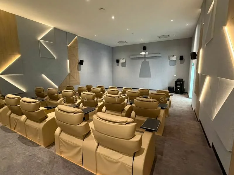 Room features: theater seating with reclining chairs in beige, acoustic wall panels, wall-mounted speakers, projector screen, recessed ceiling lights, carpeted flooring, side tables attached to seating, neutral wall color, air conditioning vents; style: modern.