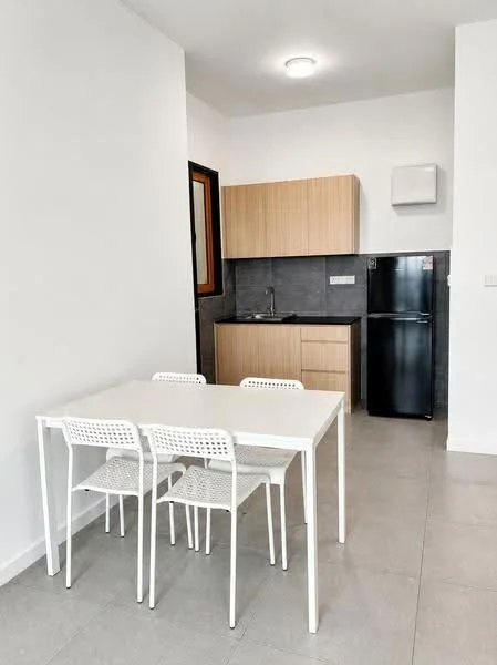 Kitchen features: white walls, grey tiled backsplash, light wood cabinetry, stainless-steel sink, chrome faucet, black fridge, white dining table, four white chairs, recessed ceiling light, grey floor tiles; style: modern.