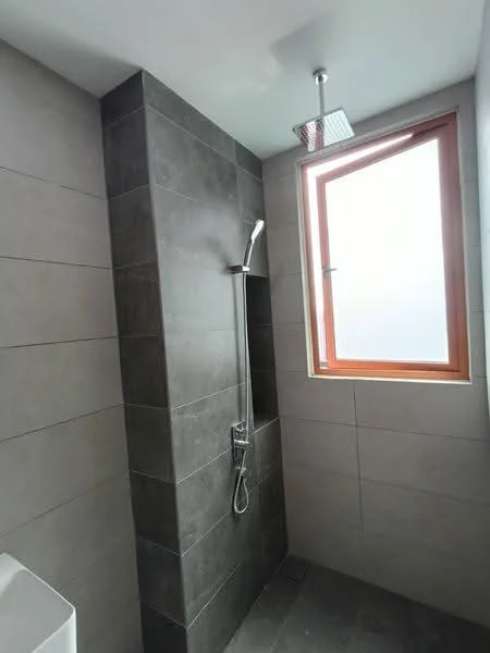 Bathroom features: walk-in shower with glass enclosure, rain shower head, handheld shower, chrome basin mixer, grey tile cladding on walls, light grey tile flooring, window with wooden frame, exposed plumbing fixtures; style: modern.