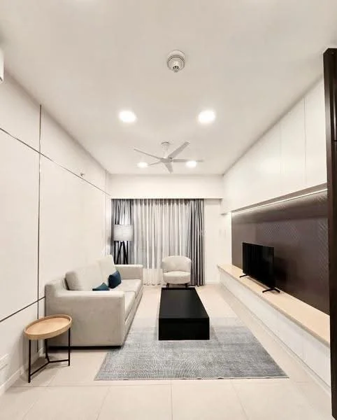 Living features: light grey fabric sofa, black coffee table, area rug with geometric pattern, wall-mounted TV, built-in cabinetry with light wood finish, floor-to-ceiling windows with sheer curtains, 5-blade ceiling fan with light, recessed LED downlights, decorative wall paneling, side table, upholstered armchair in cream; style: modern.