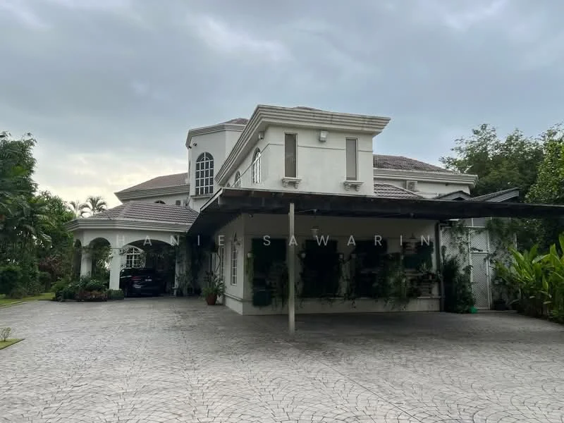 Exterior type: detached bungalow; features: white painted facade, flat roof, approximately 2-storey, manicured lawn, paved driveway, car porch with awning, landscaped garden with tropical plants, large windows, balcony on upper level, covered entrance, decorative columns; style: modern.