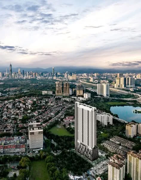 Exterior type: high-rise condominium; features: glass curtain wall, surrounded by mature greenery, city skyline view in background, manicured lawn, adjacent to highway; style: modern.