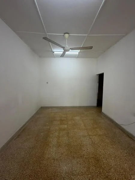 Room features: white painted walls, ceiling fan, fluorescent ceiling lights, terrazzo flooring, single door, empty space.