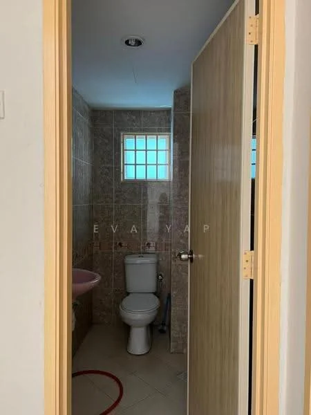 Bathroom features: one-piece toilet, single-sink vanity with wood cabinet, pink sink, tile cladding on walls, ceramic tile flooring, window with frosted glass, light fixture on ceiling, door with wood finish.