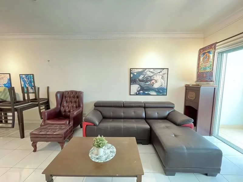 Living features: brown leather sectional sofa, red accent on sofa, brown leather armchair, wooden coffee table, white tiled flooring, framed artwork on wall, decorative plant on table, sliding glass door leading to balcony; style: contemporary.