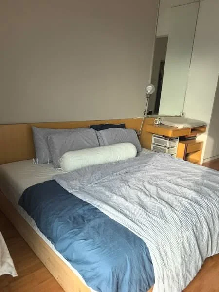Bedroom features: queen-size bed with blue and white bedding, wooden bed frame, decorative bolster pillow, nightstand with lamp, built-in wardrobe with mirror, wooden flooring, desk with storage drawers, wall-mounted mirror; style: modern.