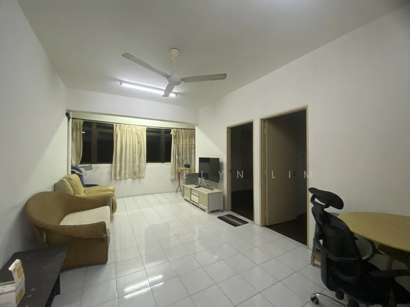 Living features: white painted walls, glossy white tile flooring, 5-blade ceiling fan, large windows with sheer curtains, sofa with wicker frame, TV console, freestanding TV cabinet, round dining table, office chair, doorway leading to other rooms.