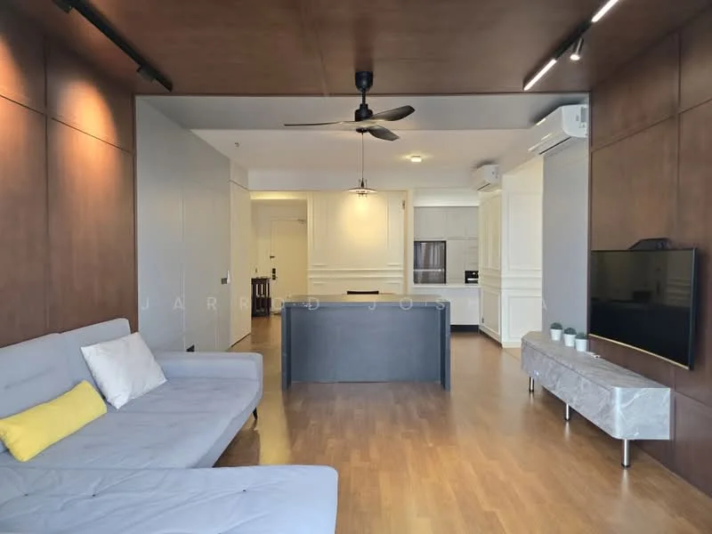 Living features: grey fabric sofa, yellow accent cushion, wooden flooring, ceiling fan, wall-mounted TV, TV console in light grey, recessed lighting, wood panel accent wall, open layout to kitchen, air conditioning unit; style: modern. Kitchen features: white cabinetry, built-in oven, refrigerator, countertop with bar seating, stainless-steel sink, chrome faucet, light grey backsplash, open layout to living area; style: modern.