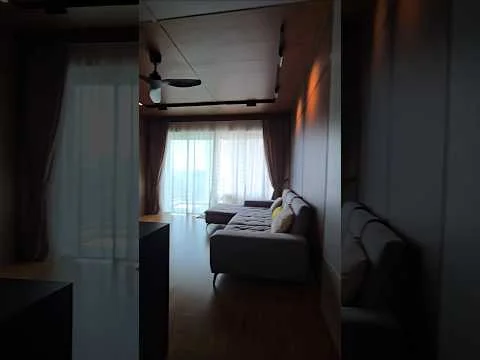 Living features: floor-to-ceiling windows, sheer curtains, 3-seater fabric sofa in light grey, sectional sofa, wooden flooring, ceiling fan, recessed downlights, decorative wall paneling, area rug, coffee table; style: modern; view: city.